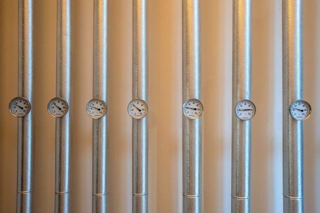 Mesurer en kWh la chaleur reçue par un appartement chauffé en commun Rangée de tuyaux verticaux équipés chacun d'un thermomètre à cadran