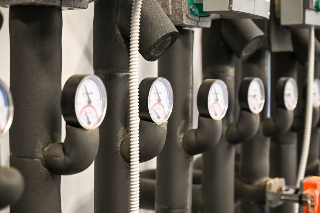 Remplacer les chaudières d'un immeuble, se raccorder ou changer d'énergie Tuyauteries calorifugées d'une chaufferie équipées d'une rangée de manomètres