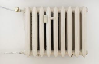 Radiateur en fonte blanc équipé d'un répartiteur de frais de chauffage fixé entre ses éléments