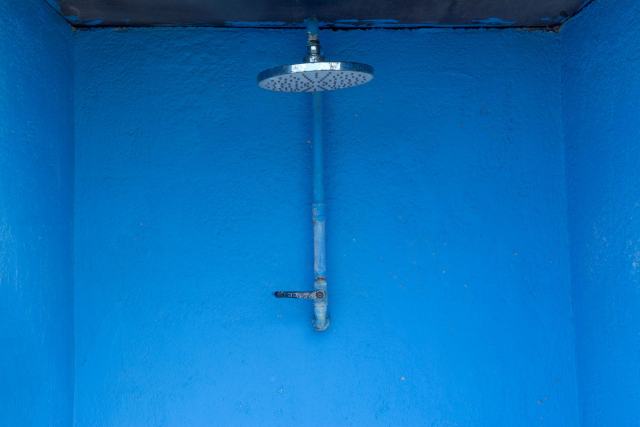Plus d'eau chaude au robinet alors que la chaudière tourne Pomme de douche fixe sur un mur peint en bleu vif
