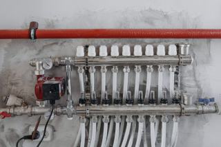 Collecteur de chauffage avec circulateur rouge et nombreux départs de tubes sous une conduite rouge