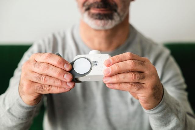 Intoxication au CO par une chaudière : causes, symptômes et gestes d'urgence Homme qui tient à deux mains un petit détecteur blanc à installer au mur
