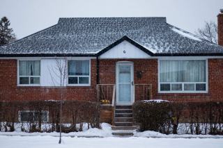Maison de plain-pied en briques au toit couvert de neige, perron et rambarde