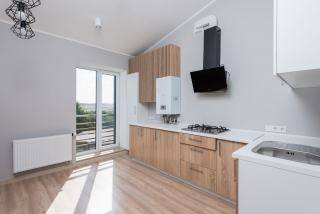 Cuisine lumineuse neuve avec chaudière murale blanche au-dessus du plan de travail et radiateur sous la fenêtre