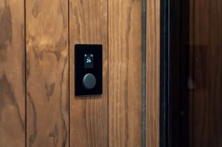 Thermostat d'ambiance noir à écran et molette encastré dans un lambris en bois