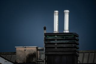 Deux conduits d'évacuation en inox dépassant d'un bloc de toiture sous un ciel bleu nuit